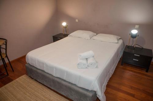 a bedroom with a large white bed with slippers on it at Quinta do Carvalho - Nature Guest Houses in Guimarães