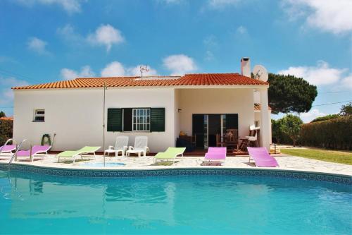 a villa with a swimming pool and purple and green chairs at Surf House in Aljezur