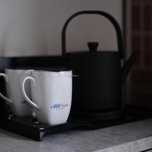 two coffee cups sitting on a tray on a kitchen counter at BW Express Jakarta Tanah Abang in Jakarta