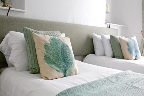 łóżko z białymi i zielonymi poduszkami w obiekcie The Dolphin Hotel Exmouth w mieście Exmouth