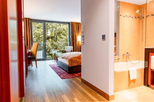 a hotel room with a bed and a bathroom at FAVORITE Parkhotel in Mainz