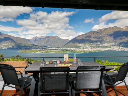 een tafel en stoelen op een balkon met uitzicht op het water bij Apartment Miralago - Utoring-21 by Interhome in Piazzogna