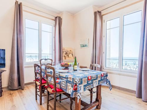 une salle à manger avec une table, des chaises et des fenêtres dans l'établissement Apartment Le Caneton-4 by Interhome, à Cabourg