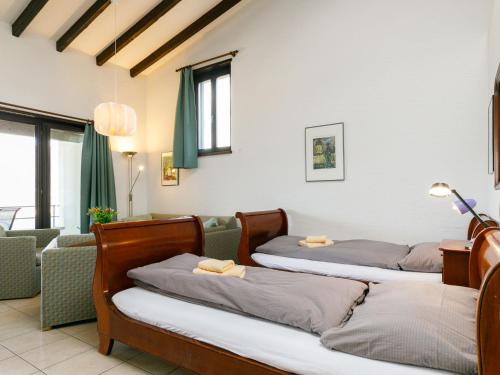 a room with three beds and a couch at Apartment Residence Miralago - Utoring Apt- A9 by Interhome in Piazzogna