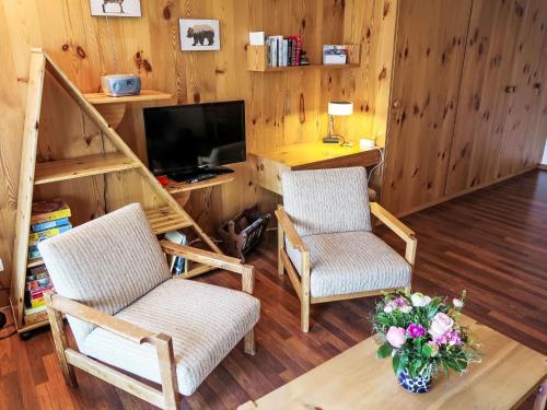 uma sala de estar com duas cadeiras e uma televisão em Apartment Utoring Acletta-84 by Interhome em Disentis