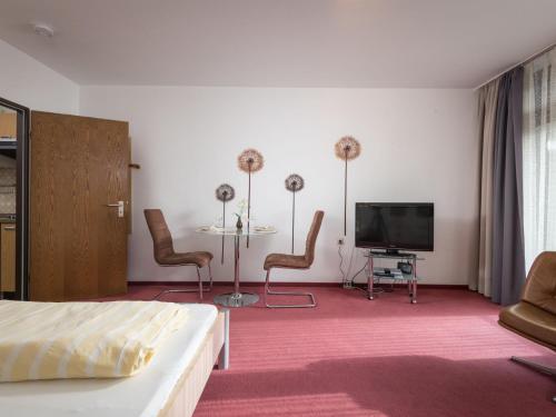 ラーンシュタインにあるApartment B1010 by Interhomeのベッド、テレビ、テーブルが備わる客室です。