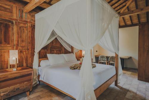 a bedroom with a white bed with a canopy at Villa Danginan & Dajanan Pemuteran in Pemuteran