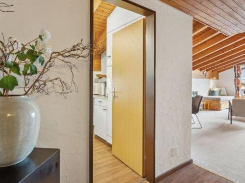 a kitchen with a yellow door and a vase on a table at Apartment A301 by Interhome in Lenzerheide