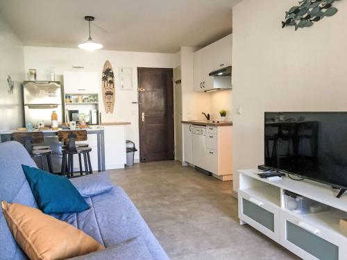 un salon avec un canapé bleu et une cuisine dans l'établissement Apartment Les Jardins d'Ys-9 by Interhome, aux Issambres