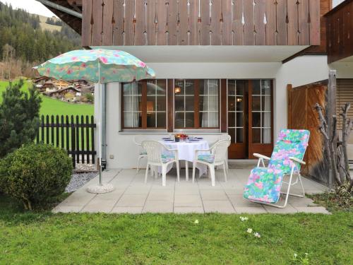 een patio met een tafel en stoelen en een parasol bij Apartment Chalet Simmental P-3 by Interhome in Zweisimmen