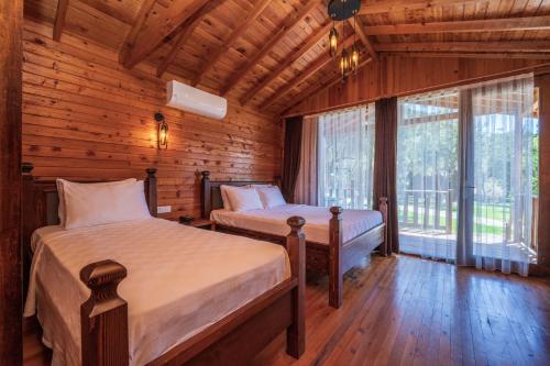 a bedroom with two beds in a log cabin at Sea Valley Lodge in Faralya