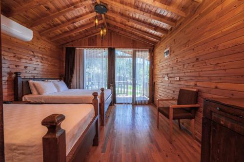 a log cabin bedroom with two beds and a chair at Sea Valley Lodge in Faralya