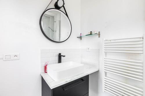 uma casa de banho com um lavatório branco e um espelho. em 2 pièces, calme et lumineux. em Boulogne-Billancourt