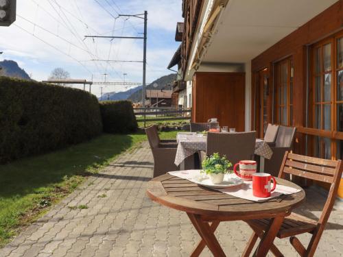een houten tafel en stoelen op een patio bij Apartment Marie-Soleil by Interhome in Gstaad
