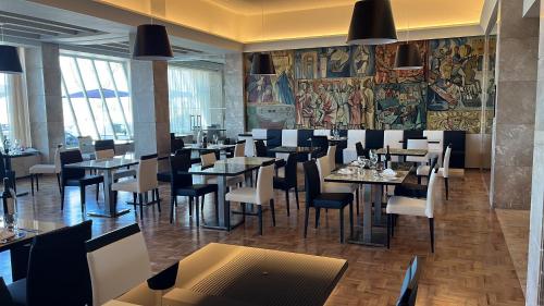 um restaurante com mesas e cadeiras e um mural em Vila Gale Collection Figueira da Foz na Figueira da Foz