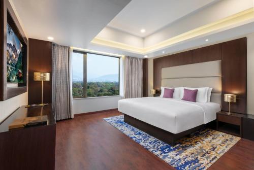 a bedroom with a large bed and a large window at Vivanta Jamshedpur, Golmuri in Jamshedpur