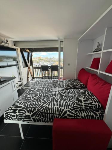 1 dormitorio con 1 cama en blanco y negro y 1 sofá rojo en Résidence port venus -au village naturiste -avec une vue sur le port et la mer en Cap d'Agde