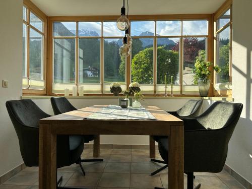 a dining room table with black chairs and windows at Ferienwohnung Marianne Bergpanorama Eröffnung Juni 24 für Paare 60qm in Berchtesgaden