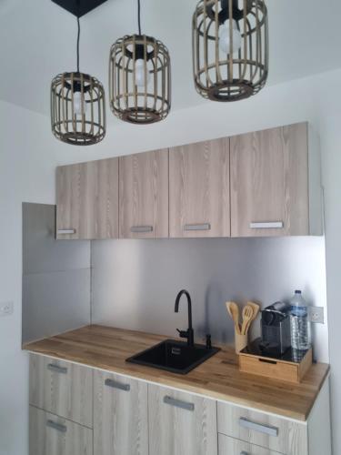- une cuisine avec deux lampes suspendues et un évier dans l'établissement Résidence Dica, à Port-Saint-Louis-du-Rhône