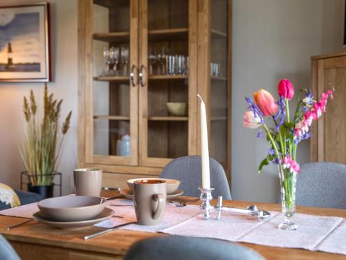 a wooden table with plates and cups and flowers on it at Apartment Nachtigall II-3 by Interhome in Osten