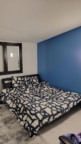 un lit dans une chambre avec un mur bleu dans l'établissement Maison 24h du Mans, à Arnage