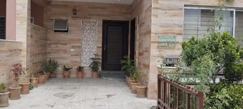 Balqees Cottage في لاهور: باب أمام منزل به نباتات الفخار