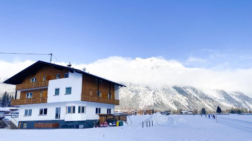 a building in the snow in front of a mountain at Appartements Wolf in Leutasch