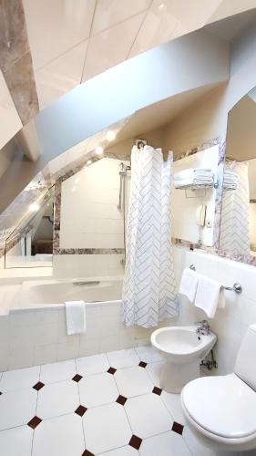 a bathroom with a toilet and a tub and a sink at BEST WESTERN Santakos Hotel in Kaunas