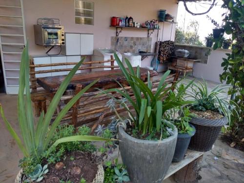 um jardim com vasos de plantas e um banco em Chalés Excalibur em São Tomé das Letras