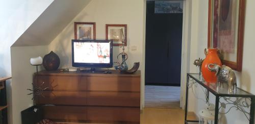 - un salon avec une commode et une télévision dans l'établissement Claude et Martine, à Villeparisis