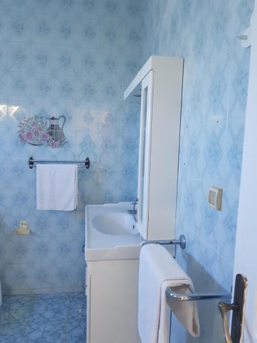 een badkamer met een witte wastafel en blauwe tegels bij Love in Midoun