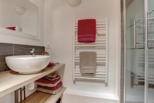 La salle de bains est pourvue d'un lavabo blanc et de serviettes. dans l'établissement Le Turenne - Noisy le Roi, à Noisy-le-Roi