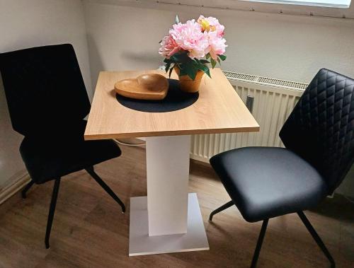 a table with a vase of flowers on it with two chairs at Stadler Ferienwohnung in Neudörfles