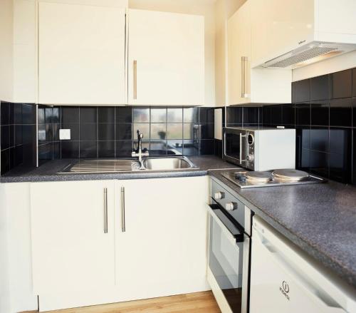a kitchen with white cabinets and a sink at Chapter Highbury I in London in London