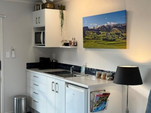 cocina con fregadero y microondas en Okauia Lodge, en Matamata