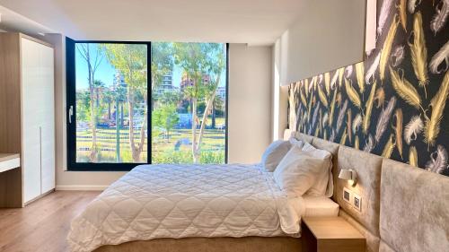 a bedroom with a large bed with a large window at Marina Premium Hotel in Vlorë