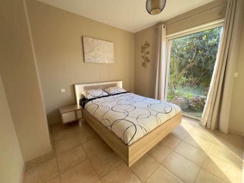 une chambre avec un lit et une grande fenêtre dans l'établissement 72 m2 Centre-ville avec jardin, à Porto-Vecchio