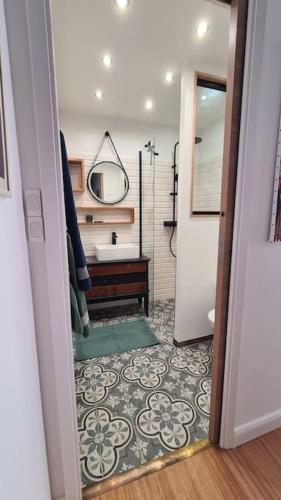 - un couloir avec une salle de bains pourvue d'un lavabo et d'un miroir dans l'établissement Appartement Ajaccio proche plage, à Ajaccio