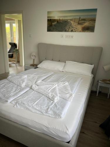 a white bed with white sheets and pillows on it at Die lütte Welle Grömitz in Grömitz