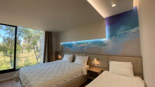 a bedroom with two beds and a painting on the wall at Marina Premium Hotel in Vlorë
