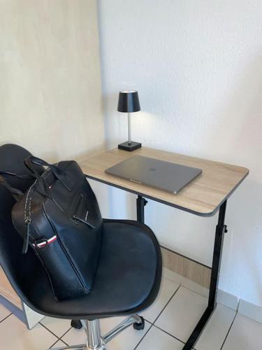 a desk with a laptop and a chair with a bag at Le Sun Valley - Studio Cosy - Free Parking in Montpellier