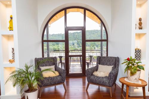 a living room with two chairs and a large window at Villa Vermont Qusar in Qusar