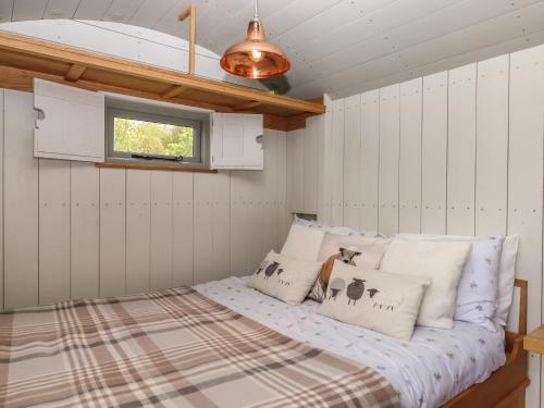 a bedroom with a bed with white walls and a window at Burr 1 Shepherds Hut in Barnstaple