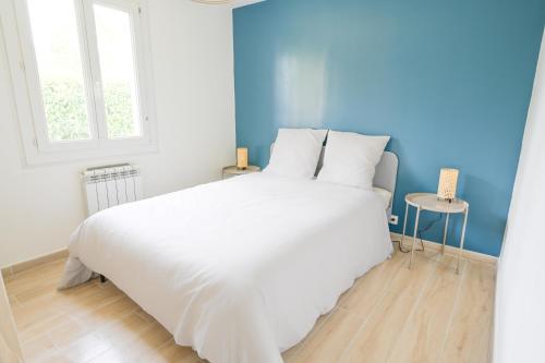 białe łóżko w pokoju z niebieską ścianą w obiekcie Le Quartz - Grande Maison avec piscine - Tournefeuille w mieście Tournefeuille
