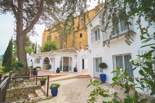 une maison blanche avec un arbre et des escaliers dans l'établissement Hotel Boutique Palacio De La Duquesa, à Ronda