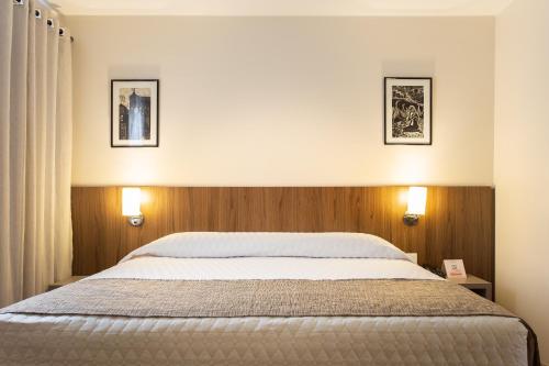 a bedroom with a bed and two pictures on the wall at Hotel Dom Rafael Premium in Santa Maria