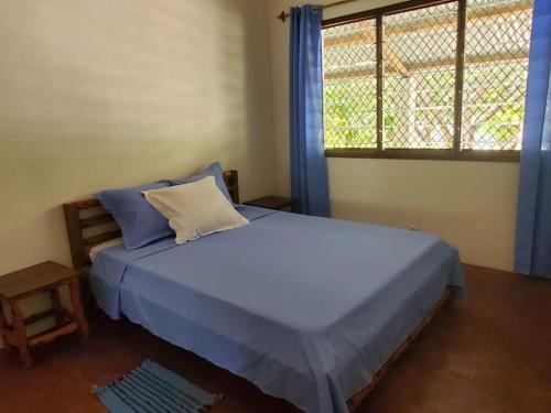 Un dormitorio con una cama con sábanas azules y una ventana. en Charmante villa familiale proche de la mer, en Mahajanga