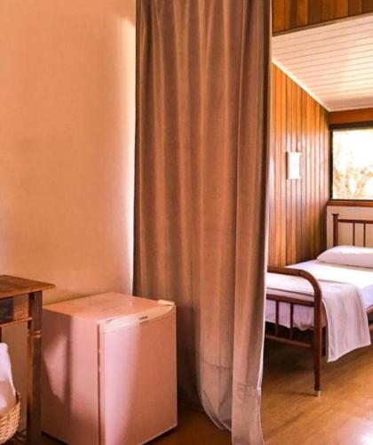 a bedroom with a bed and a window with a curtain at Pousada Caminhos de Gaia in São Francisco Xavier