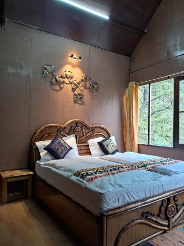 a bedroom with a large bed with a wooden headboard at Thehraav By The River - Mudhouse Odyssey, Tirthan Valley in Banjār