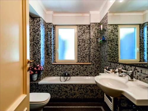 a bathroom with two sinks and a tub and a toilet at Pirandello Apartment Acitrezza in Aci Castello